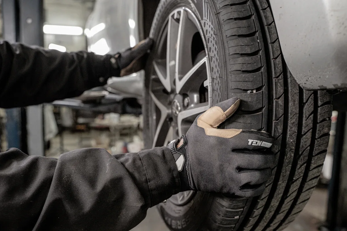 Mechanic in work gloves inspecting tire tread depth during vehicle maintenance