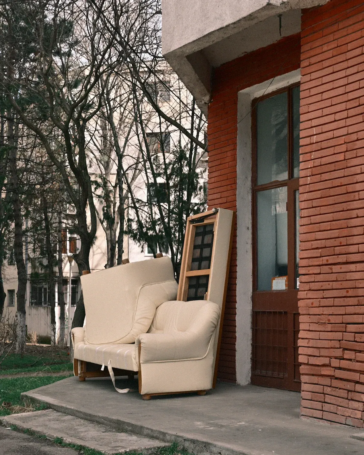 Cream armchair and wooden ladder leaning against red brick building exterior