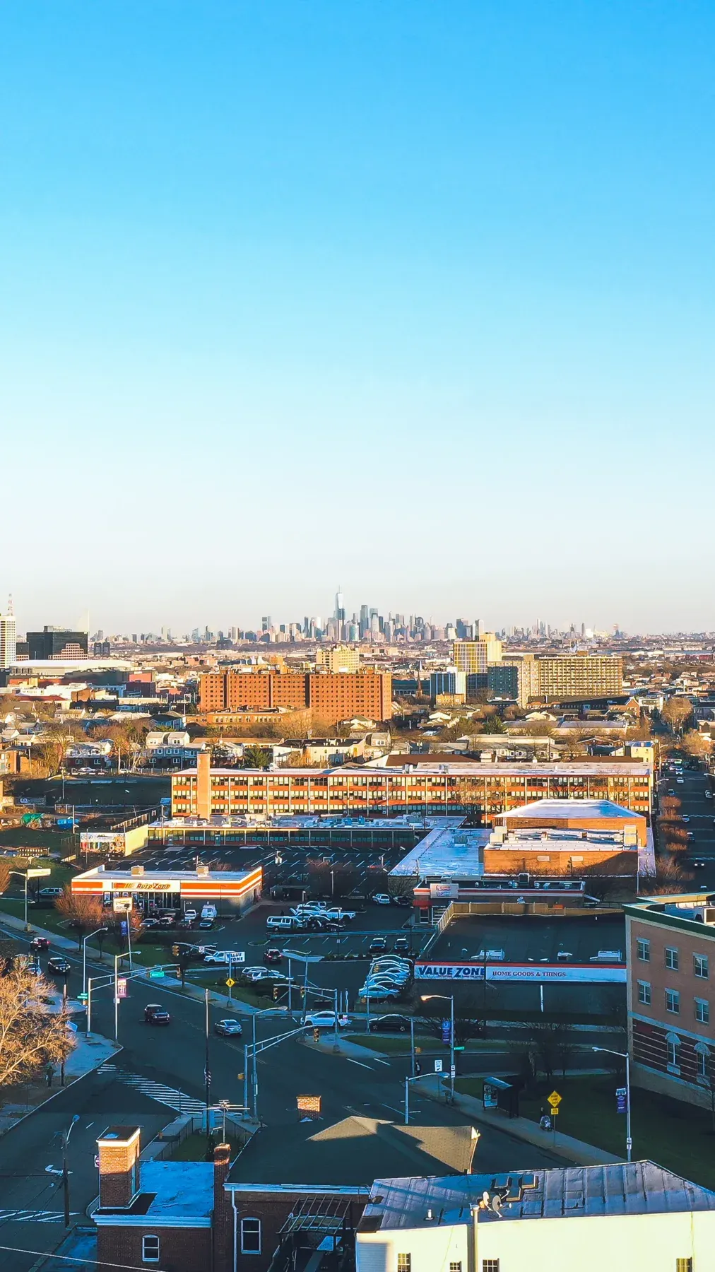 Elevated view of Queens neighborhood with Manhattan skyline in distance under clear blue sky